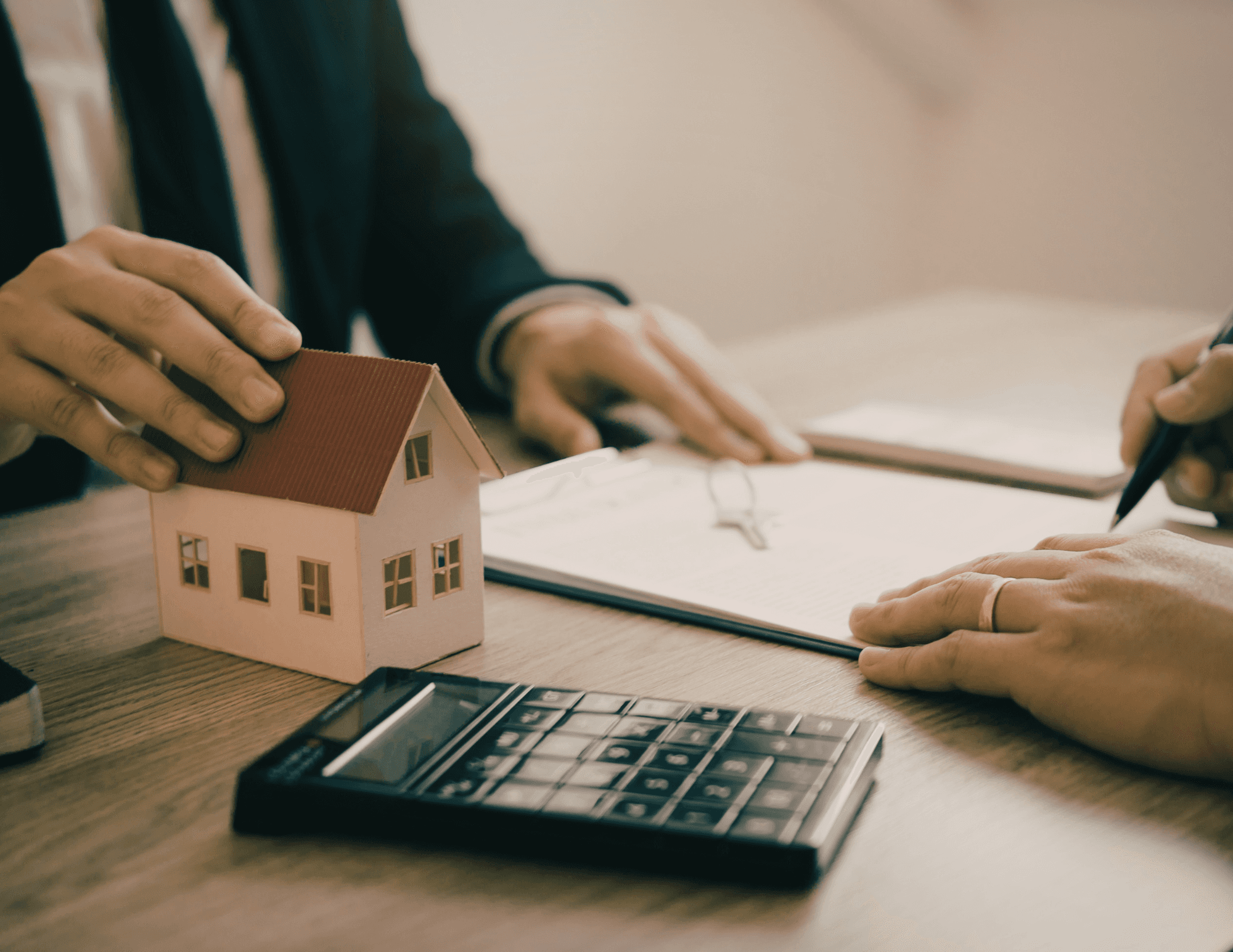 Model house and calculator on a desk during a deal review